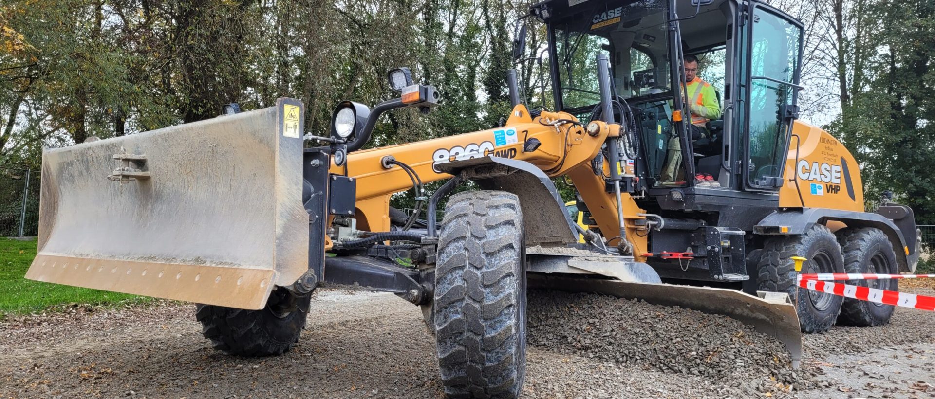 Eine große Baumaschine ebnet auf einem Weg den Kiesboden